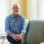 Portrait of contented senior man sitting on armchair's hand rest at home